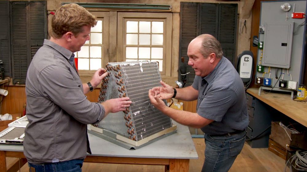 Photo of two people looking at an air conditioning system that uses Freon, which is now a banned chemical.