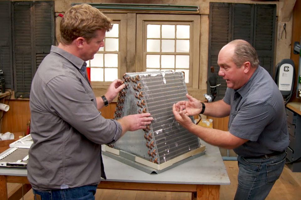 Photo of two people looking at an air conditioning system that uses Freon, which is now a banned chemical.